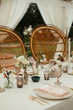 the table is set with flowers, candles and place settings for an outdoor wedding reception