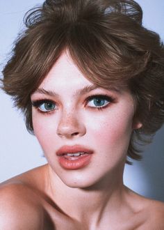 a woman with freckled hair and blue eyes is posing for a photo in front of a white background