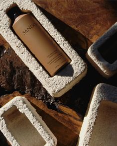 a bottle of sand sitting on top of some concrete blocks next to rocks and dirt