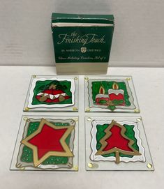 four glass christmas ornaments in front of a box