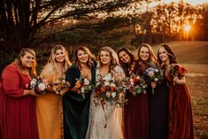 a group of women standing next to each other holding bouquets in their hands and smiling at the camera