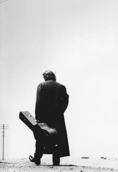 a man with a suit case walking down the street in front of an electric pole