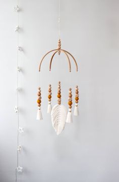 a mobile made out of wood beads and feathers hanging from a string on the wall