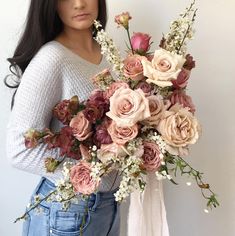 a woman holding a bouquet of flowers in front of her face and looking at the camera