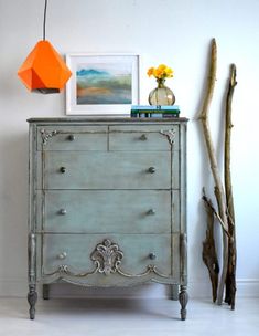 an old dresser is painted blue and has flowers on the top, along with other items