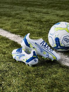 two soccer balls sitting on top of a grass field next to a white and blue line