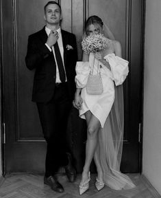 a man in a suit and tie standing next to a woman wearing a wedding dress