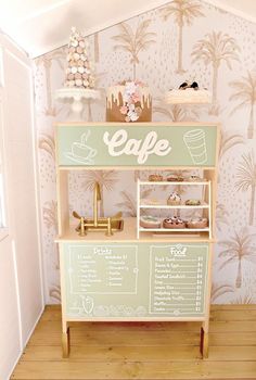 a green and white coffee shop display on wooden floor next to wall with palm trees