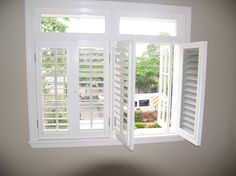 an open window with shutters on the outside and inside, in front of a white wall