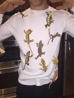 a man wearing a white shirt with geckos on it's back and fingers in his ears