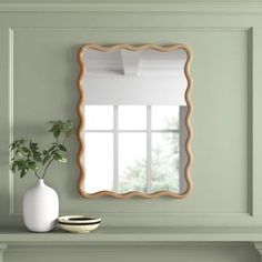 a white vase sitting on top of a table next to a mirror and fireplace mantel