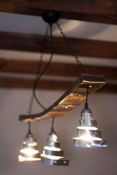 several lights hanging from the ceiling in a room with wood beams and metal fittings