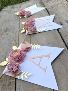 some paper flowers are laying on top of a wooden table with gold foil and pink roses