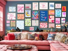 a living room filled with pink couches and lots of pictures on the wall above them