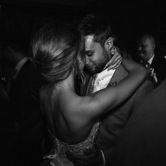 a man and woman hugging each other at a wedding reception in black and white photo