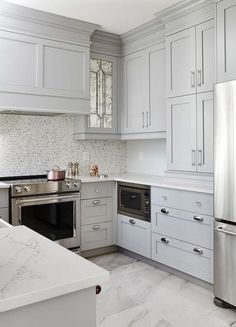 a white kitchen with marble counter tops and stainless steel appliances