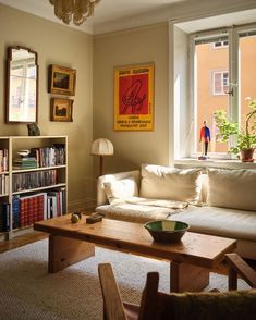 a living room filled with furniture and a book shelf next to a large open window