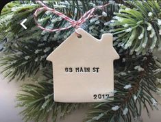 a ceramic house ornament hanging from a christmas tree