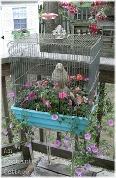 a bird cage with flowers in it sitting on top of a table