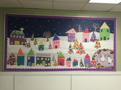 a bulletin board is decorated with colorful houses and trees in the snow on a green wall