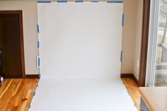 an empty room with a white backdrop in the middle and blue tape on the floor