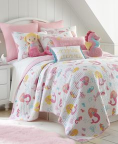 a bed with pink and white bedspread, pillows and stuffed animals