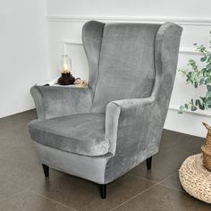 a grey chair sitting on top of a tile floor next to a potted plant