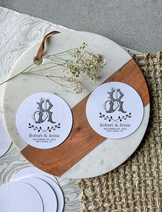 two round stickers on top of a wooden cutting board next to some white plates