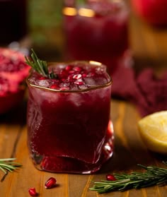 a drink with cranberry and rosemary garnish sits on a wooden table