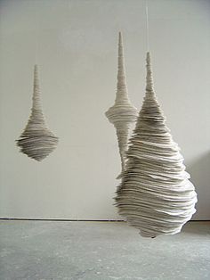 three white sculptures hanging from strings in a room