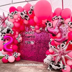 pink and black balloons are on display in front of a wall with cowgirl decorations