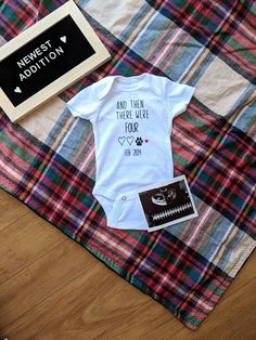 a baby's first birthday outfit on top of a plaid blanket next to a chalkboard