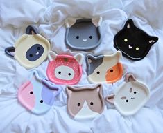 six cat shaped dishes on a bed with white sheets