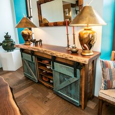 a wooden table with two lamps on top of it next to a mirror and chair