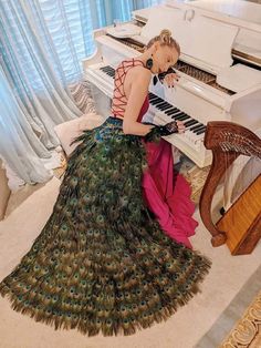 a woman in a peacock dress playing the piano