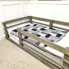 a wooden bunk bed with a quilt on the bottom and mattress in between two sides