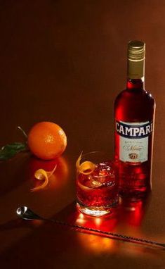 a bottle of campari next to an orange