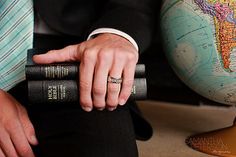 a man in a suit and tie holding two books with his hands on top of them