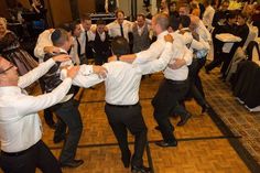 a group of men dancing on top of a wooden floor in front of a crowd