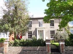 a large brick house with trees and bushes around it