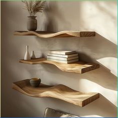 three wooden shelves with vases and books on them against a wall in a living room