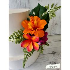 an orange and pink flower on top of a white cake with greenery around it