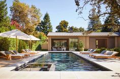 an outdoor swimming pool with lounge chairs and umbrellas