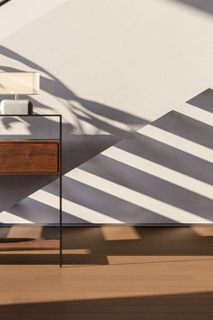 a white sink sitting on top of a wooden cabinet next to a wall with shadows