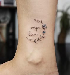 a small tattoo on the ankle that says carpe dien with blue flowers around it