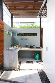 an outdoor kitchen with a sink and stove in the center, under a pergolated roof