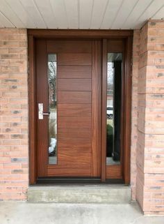 a wooden door with two sidelights and glass panels on the front of a brick building