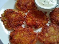 some fried food on a white plate with a small bowl of ranch dressing next to it