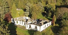 an aerial view of a large white house in the middle of some trees and grass