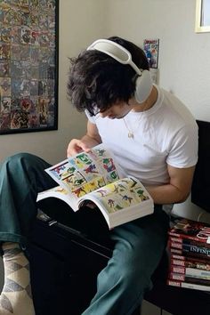 a person sitting down reading a book with headphones on their ears and looking at comics